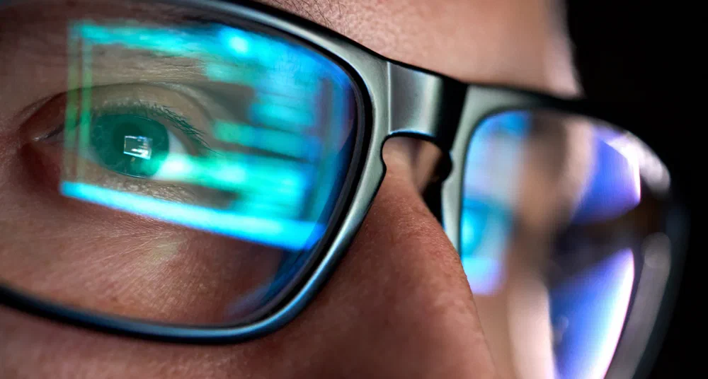 Close-up of eyeglasses reflecting lines of code - developer intently reviewing code on screen